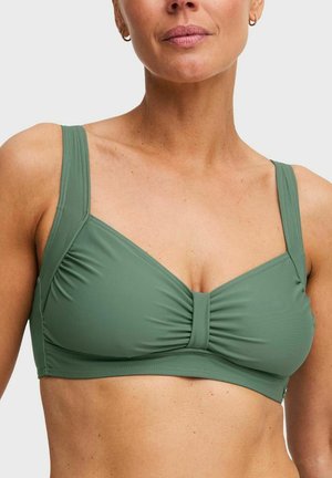 Vrouw die een olijfgroene bikinibovenkant draagt met brede bandjes en een geplooid middenstuk, zichtbaar van schouders tot middenrif.