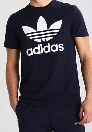 Camiseta de algodón azul marino con un gran logo blanco de Adidas con un diseño de trébol clásico. Cuello redondo y mangas cortas.