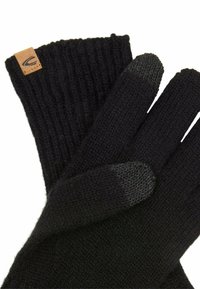 Schwarze gestrickte Handschuhe mit gerippten Bündchen, die ein Leder-Logo-Patch aufweisen. Die Fingerspitzen haben eine strukturierte Oberfläche für die Nutzung von Touchscreens.