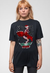 Black cotton t-shirt featuring a vibrant, graphic print of a character in a red dress with a Santa hat, accented by white and green details.