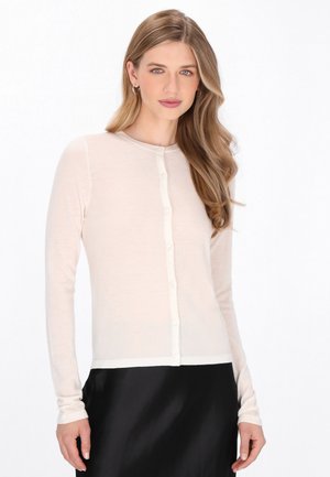 Lichte, crèmekleurige cardigan met lange mouwen, ronde halslijn en knoopsluiting aan de voorkant. De stof is zacht met een gladde textuur.