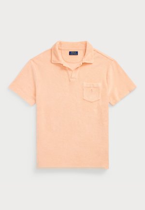 Polo manches courtes couleur pêche avec petite poche poitrine et col ouvert, avec étiquette Polo Ralph Lauren à l’intérieur du col.
