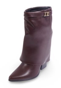 Botte de cheville en cuir brun avec un design flou, bout pointu et talon carré. Présente un accent en métal doré au niveau du poignet.