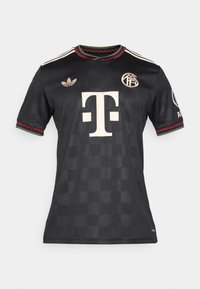 Jersey atlético negro hecho de una tela suave. Presenta acentos en blanco y rojo, un cuello redondo con un patrón texturizado, y parches de logo en las mangas.