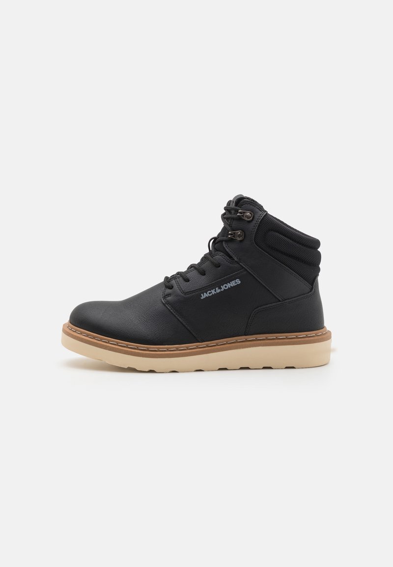 Zwarte, hoge boots van synthetisch leder met een gestructureerde afwerking, voorzien van een rubberen zool en een contrasterende beige buitenzool. Vetersluiting.