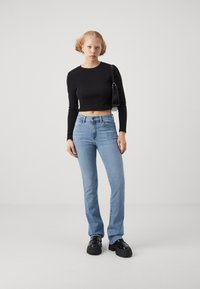 Svart kortärmad topp, ljusblå höglivade raka jeans, svarta plattformsskor och en liten svart handväska.