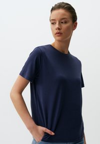 Marinetrans blauwe t-shirt met korte mouwen, gemaakt van zacht, glad stof; heeft een ronde halslijn en een relaxed fit, met een ingeschoven hand detail aan de zijkant.