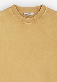 Felpa in cotone giallo senape con colletto rotondo a costine, caratterizzata da una superficie testurizzata e sottili variazioni di colore. Etichetta del marchio visibile.