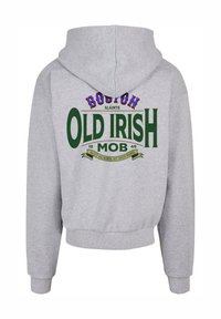 Pelēks džemperis ar kapuci, kuram mugurpusē ir spilgti zaļš un daudzkrāsains teksts: "BOSTON OLD IRISH MOB 1846" ar dekoratīviem akcentiem.