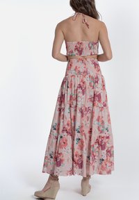 Completo floreale a due pezzi con top bandeau arricciato e gonna maxi a strati. Il tessuto è leggero e presenta motivi floreali rosa e multicolori.