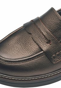 Mocasín de cuero marrón con un acabado texturizado, que presenta una tira cosida en el empeine y una suela en contraste para un detalle adicional.