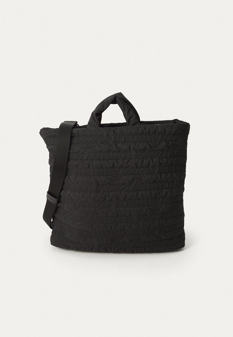 Black quilted tote bag with a textured pattern, featuring short handles and an adjustable shoulder strap. Smooth fabric with soft finish.