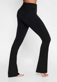 Svarta utsvängda leggings med hög rynkad midjereså och en slät yta, som har en tight passform från midjan ner till anklarna.