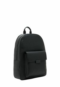 Mochila de cuero negro con forma redondeada, bolsillo frontal con solapa, dos asas superiores y textura suave. Cierre de cremallera y diseño minimalista.