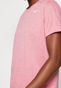 Camiseta Nike de color rojo jaspeado, fabricada en una mezcla de algodón, de mangas cortas, con cuello redondo, que presenta un logo blanco en el hombro izquierdo.