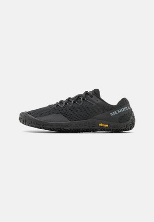 Sapatilhas de trail running pretas com parte superior em malha, sola texturizada e marca Vibram. Apresentam um perfil baixo e atacadores tradicionais para ajuste.