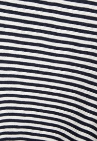 Tessuto a righe blu navy e bianche con un motivo a maglia strutturato. Le righe alternano larghezza, creando un design orizzontale ben definito.