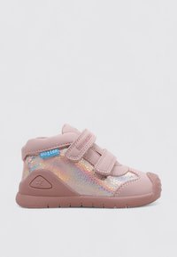 Chaussures pour enfants roses avec un panneau brillant et irisé, des sangles Velcro et une semelle en caoutchouc avec un embout texturé et des accents de logo.