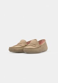 Beige semskede loafer med rund tå, med stikninger på overdelen og en blød indersål. Flad gummisål.