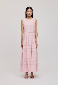 Dlouhé růžové šaty se čtvercovým výřezem, bez rukávů a s plynule se rozšiřující sukní sahající až ke kotníkům.