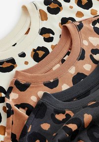 Drei Crewneck-Sweatshirts werden präsentiert. Farben: beige mit schwarzen und braunen Leopardenflecken, Rost mit schwarzen Flecken und schwarz mit beige-farbenen Flecken. Weicher Stoff.