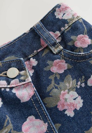 Džínovina s modrým a růžovým květinovým vzorem, obsahující kovový knoflík a světle hnědé prošití na pase a švech.