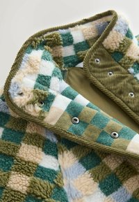 Jachetă din fleece cu un model în carouri verde, albastru și crem. Textură moale, cu închideri prin capse și interior din bumbac cu țesătură corduroy în contrast.