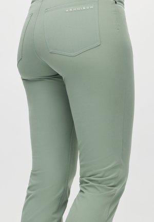Light green, fitted pants made of smooth fabric. Features a back pocket with a stitched logo and a subtle texture in the fabric.