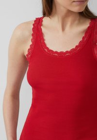 Rotes geripptes Tanktop mit Rundhalsausschnitt und zarter Spitze an den Trägern. Der Stoff wirkt weich und eng anliegend.