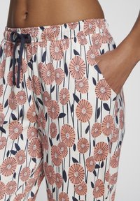 Cotton floral print pants featuring a peach and navy design with pockets. The waistband has an adjustable drawstring for added comfort.