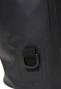 Bolsa impermeable negra con superficie texturizada, que cuenta con una correa y un anillo en D de metal para sujeción, destacando su diseño funcional y durabilidad.