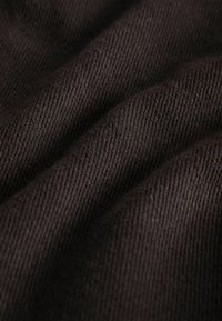 Tissu brun foncé avec une texture en sergé diagonal, montrant des plis doux et des motifs de fils visibles.