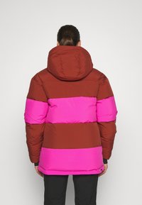 Veste rembourrée à rayures horizontales marron et rose, avec une capuche et des poignets élastiques, conçue avec une texture lisse.
