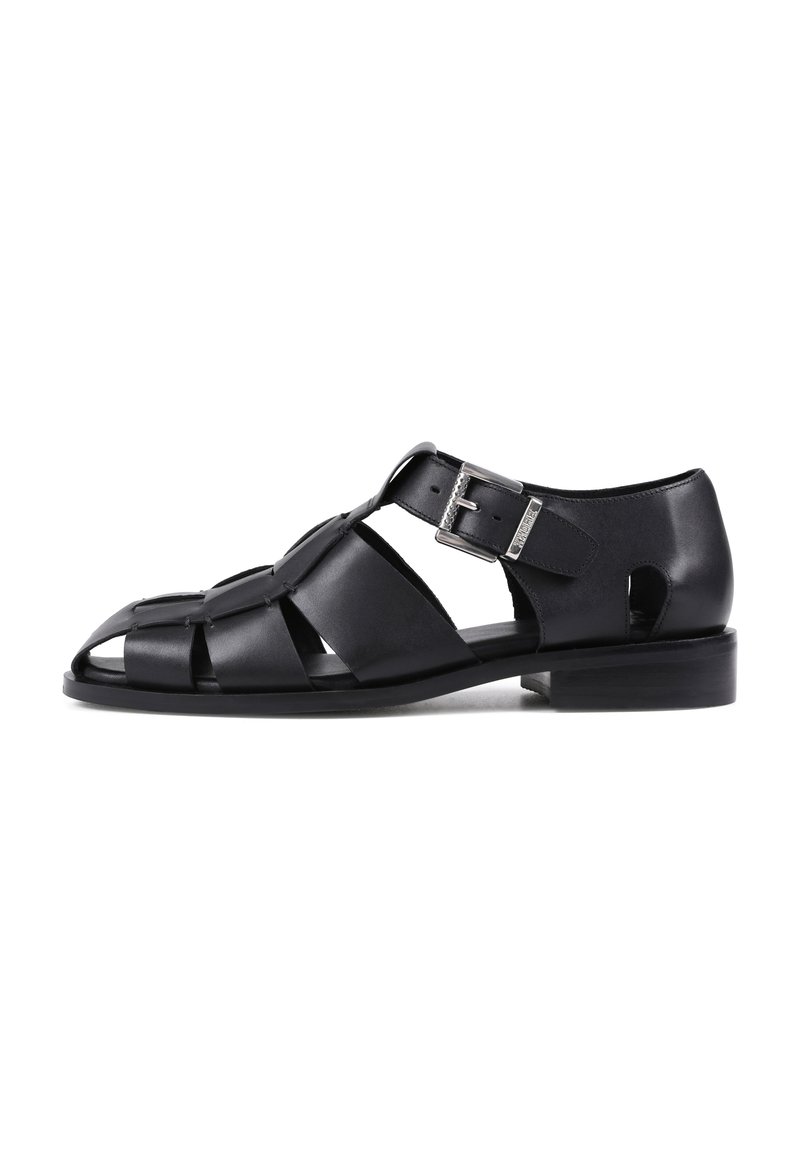 Sandales en cuir noir avec un design découpé, système de fermeture à boucle et talon bas. Caractéristiques d'une semelle plate et d'un bout ouvert pour la respirabilité.