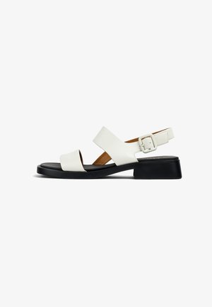 Weiße Ledersandalette mit zwei breiten Riemen, einer hinteren Schnalle und einer kontrastierenden schwarzen flachen Sohle für Stabilität und Komfort.