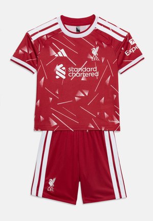 Rotes Liverpool FC Fußballtrikot mit geometrischem Muster, weißen Streifen auf Schultern und Shorts sowie Sponsorlogos auf Shirt und Ärmel.
