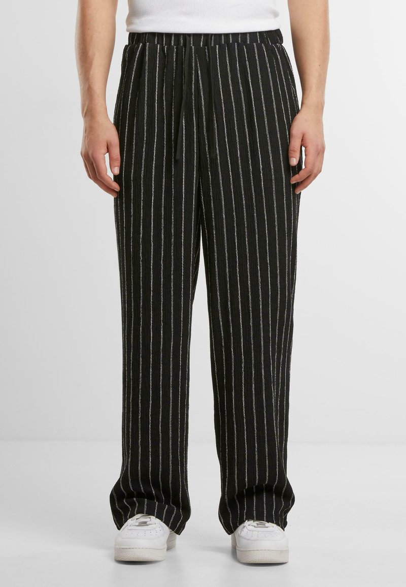 Pantaloni negri cu dungi și accente argintii, dotati cu un tiv elastic și șnur de ajustare. Materialul are un aspect texturat și o croială lejeră.