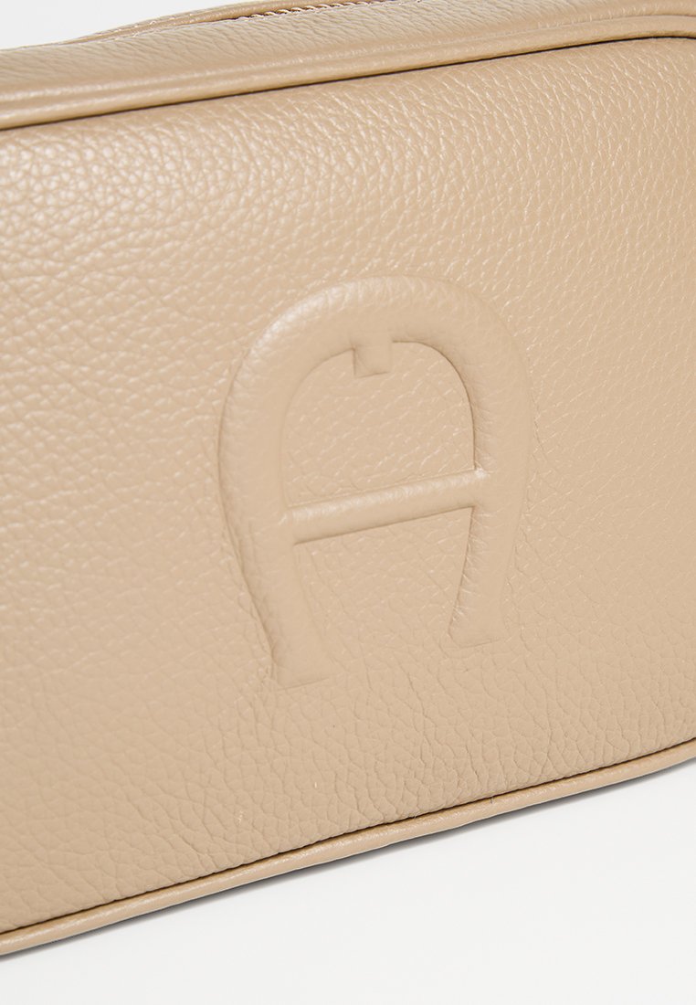 Beige Lederhandtasche mit einer strukturierten Oberfläche und einem geprägten Logo mit dem runden Buchstaben "A". Kompakte rechteckige Form mit einem Reißverschluss.