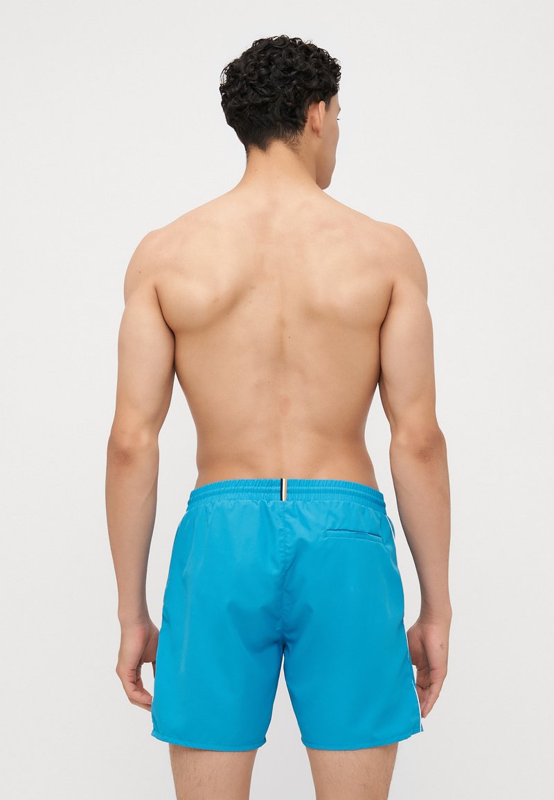 Blauwe zwembroek met een smooth, glanzende textuur. Voorzien van een elastische tailleband, een achterzak en witte accentdetails.