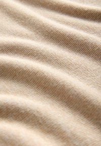 Beige stoffen textuur met een zachte, licht geribbelde oppervlakte, met subtiele kleurvariaties en een soepele, rekbare feel.