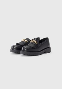Black leather loafers with a textured finish, featuring a decorative gold chain and fringed accents. Chunky rubber sole for added grip.