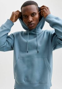 Světle modrá mikina s kapucí z měkké tkaniny, která má přední kapsu, nastavitelné šňůrky a uvolněný střih s žebrovanými manžetami.