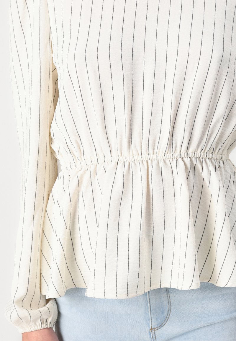 Top blanco con Rayas verticales negras, que presenta un diseño peplum y cintura fruncida. Manga larga con puños elásticos, tela ligera.