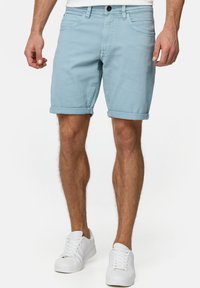 Lichtblauwe denimshorts met een opgevouwen omslag, voorzien van voorzakken en een knoopsluiting. Draag ze met witte sneakers.
