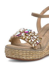Sandale compensée beige avec une plateforme en jute texturée. Comprend une sangle décorative ornée de strass multicolores et une fine bride de cheville.