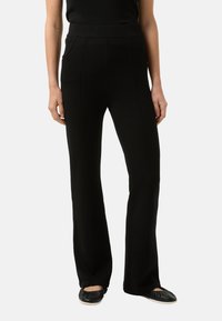 Schwarze, ausgestellte Hose mit glatter Textur, hohem Bund und Vorder Taschen. Verfügt über vertikale Nähte für ein maßgeschneidertes Aussehen.