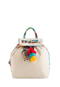 Mochila de algodón en color natural, con un asa de tela estampada colorida, un cierre con cordón y tres pompones decorativos.