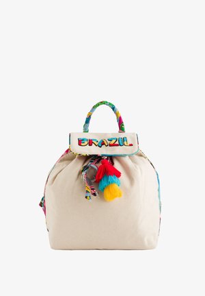 Sac à dos en coton de couleur naturelle, avec une anse en tissu à motifs colorés, une fermeture à cordon et trois pompons décoratifs.
