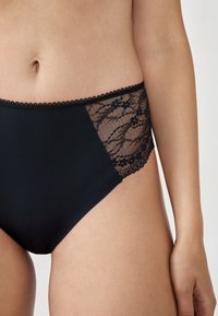 Czarne majtki o wysokim stanie z koronkowym panelem po boku, z falbanii koronkowej i gładkiego materiału dla wygody.