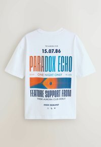 Hvid T-shirt med flerfarvet tekst, der promoverer "Paradox Echo"-begivenhed den 15.07.86 på The Aurora Club, med grafik og støtteinformationer.